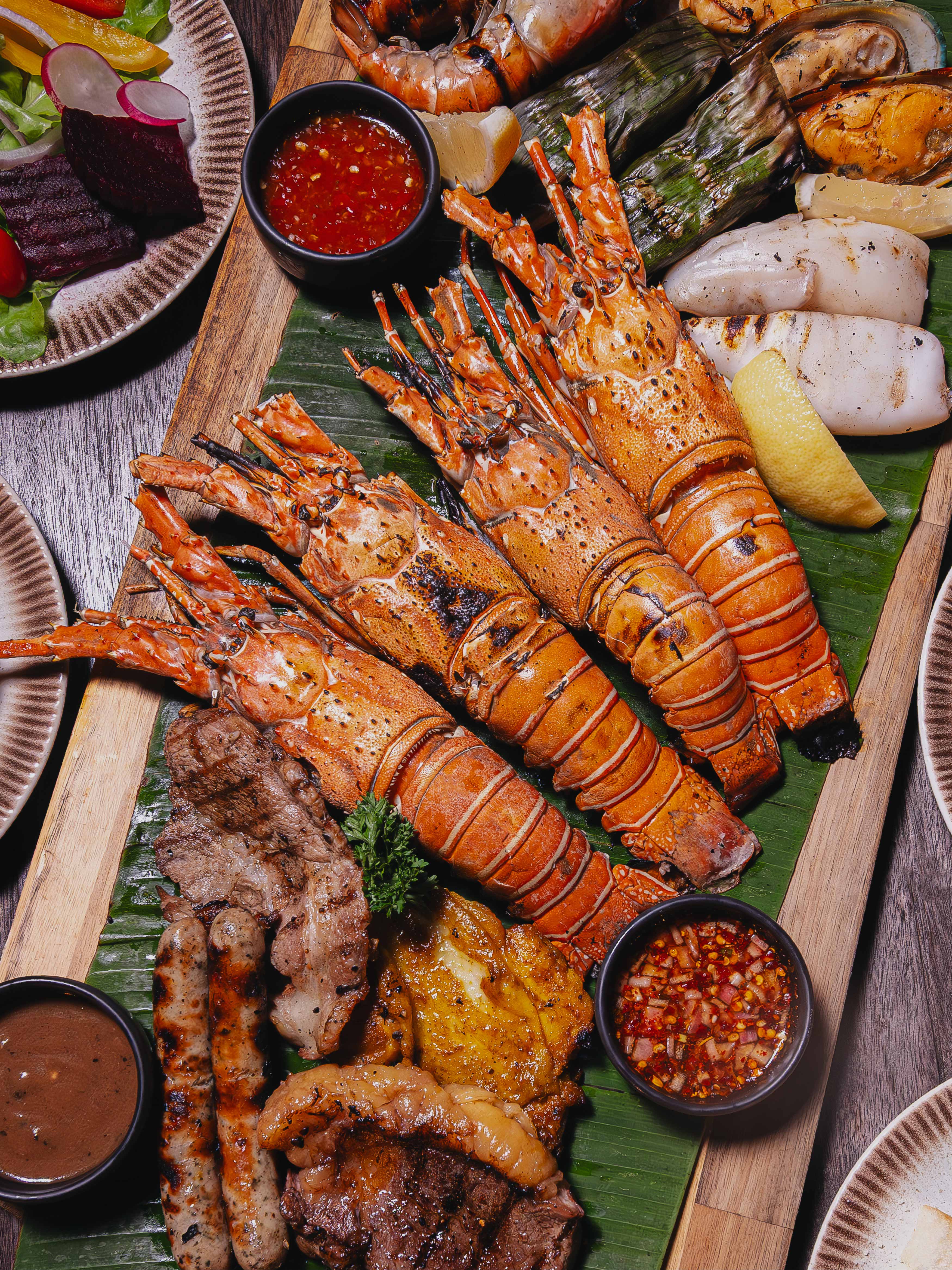 Experience Unlimited Lobster Night with Phuket lobster, BBQ seafood, premium meats, oysters, fine cheeses, and live music, enjoyed by the lake with refreshing breezes and live cooking stations.